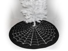 a black and white photo of a spider web on a round tablecloth with a tree in the center