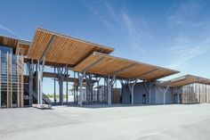 an empty parking lot next to a building with wooden roofing and glass windows on the sides