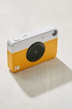 a yellow and white camera sitting on top of a table