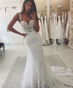 a woman in a wedding dress taking a selfie with her cell phone while looking at it