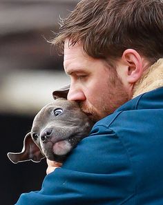 a man holding a small dog in his arms