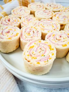 a white plate topped with rolls covered in pink and yellow frosting on top of a table