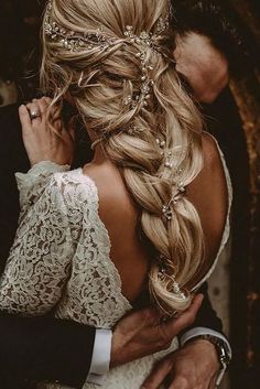 the back of a bride's head with her hair in a low ponytail and braid