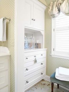 a bathroom with white cabinets and drawers in it