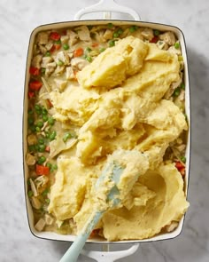 a casserole dish with mashed potatoes and peas