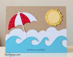 a handmade card with an umbrella and sun on the beach in front of waves