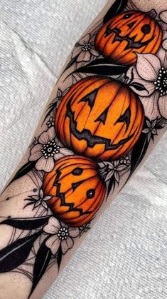 a tattoo with pumpkins and flowers on the arm, as well as an arrow