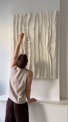 a woman is painting on the wall with white paint