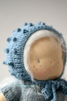 the doll is wearing a blue knitted hat