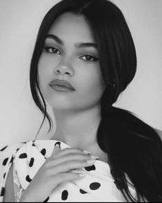 a black and white photo of a woman wearing a polka dot dress with her hands on her chest