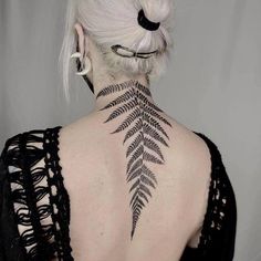 the back of a woman's neck has a fern tattoo on it