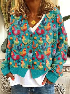 a woman standing in front of a mirror wearing a blue sweater with colorful birds on it