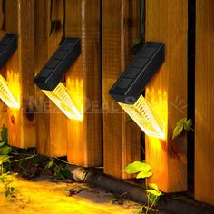 three solar powered lights on the side of a wooden fence