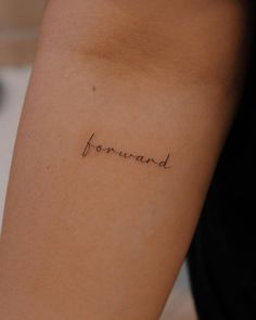 a woman's arm with the word forward tattooed on her left side, in cursive font