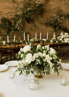 a table with white flowers and greenery on it is set up for a wedding reception