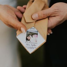 two hands holding an ornament with a couple's wedding photo on it