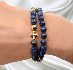 Handmade five decade Rosary Bracelet with  6mm Lapis Lazuli Ave beads.  Pater beads are 6 mm gold plated lava rock beads.  Accent beads are tarnish resistant gold tone. This five decade travel rosary is strung on flexible, durable stretch cord. The length of the rosary is approx. 7.5 inches. The rosary will fit a 6.5 inch wrist up to a 8 inch wrist comfortably. Most wrists will have a double row of beads with a gold tone Cross to complete the rosary.  This travel rosary will be used to count prayers, meditate and is a thoughtful gift for travelers, truckers and anyone on the road.. Use it in your car on the rear view mirror, keep it in your pocket while on the road, and use it as a decorative way to enhance an outfit while being a tool for meditation and keeping track of prayers.  This ver Decade Rosary, Catholic Rosary, Lapis Lazuli Beads, Rosary Bracelet, Rosary Catholic, Mens Beaded Bracelets, Stackable Bracelets, Lava Rock, Travel Gifts