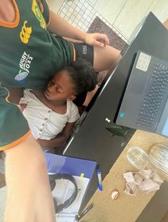 a young child is sleeping on the lap of an adult in front of a computer