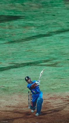 a man swinging a baseball bat on top of a field with green grass in the background