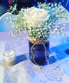 a vase filled with white flowers sitting on top of a table next to a candle