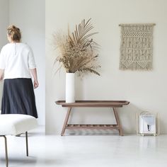 a woman standing next to a table with a plant on it