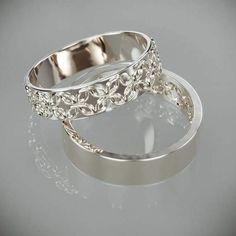 two silver rings sitting next to each other on top of a white surface with reflections