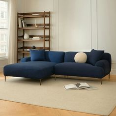 a blue sectional sofa sitting on top of a wooden floor next to a book shelf