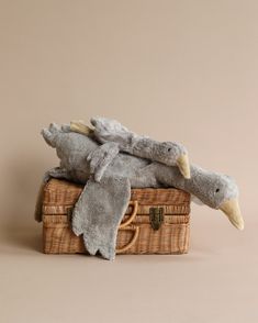 two stuffed animals sitting on top of a wicker suitcase