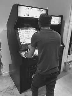 a man standing in front of an old fashioned pinball arcade machine playing the game