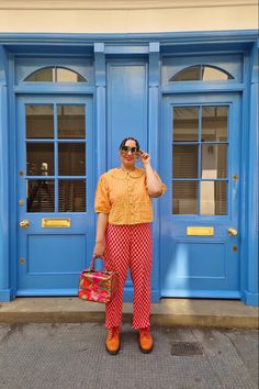 a man standing in front of a blue door talking on a cell phone and holding a suitcase