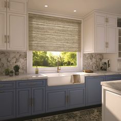 a kitchen with marble counter tops and blue cabinets, along with a window covered in roman shades