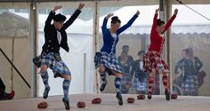 three men in kilts are jumping on stage