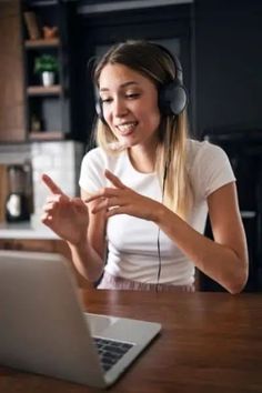 a woman wearing headphones is using her laptop