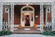 an entrance to a brick building with white ironwork and pumpkins on the steps