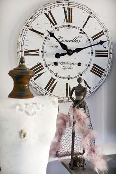 a large white clock sitting on top of a table next to a vase and lamp