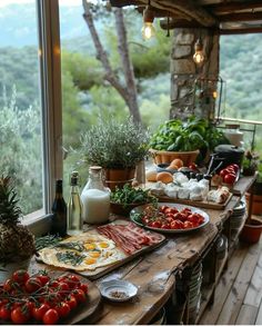 a wooden table topped with lots of food on top of a wooden floor next to a window