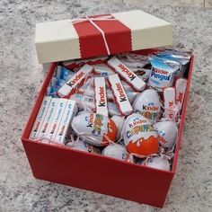 an open red box filled with candy and wrapped in white paper on top of a marble counter