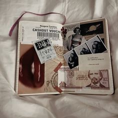 an open book with pictures and other items on it sitting on a white bed sheet