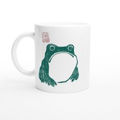 a coffee mug with a frog drawn on it's side and chinese characters in the background