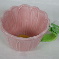 a pink glass bowl sitting on top of a white table next to a green object