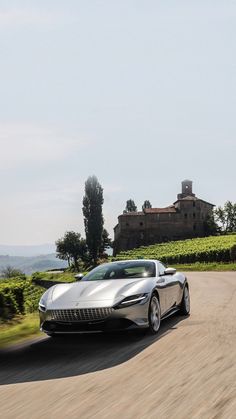 a silver sports car driving down a country road