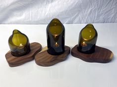 three wine bottles with candles in them sitting on wooden coasters