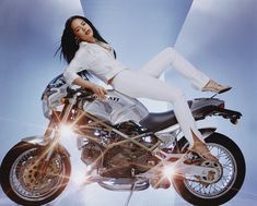 a woman sitting on top of a motorcycle in front of a blue and white background