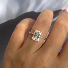 a woman's hand with a diamond ring on top of her finger and an engagement band