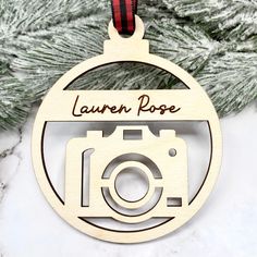 a wooden ornament with a camera hanging from it's side on a christmas tree