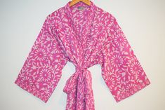 Long cotton kimono robe with stitched placket detail and pockets. Matching belt, interior ties and hanging loop at inside back neck. 100% lightweight cotton | hand block printed in Jaipur, India Size S/M: 45" length | 15" sleeve length | 53" total body width Size L/XL: 47" length | 16" sleeve length | 62" total body width Machine wash cold in water on delicate cycle | Air dry Cotton Robe With Tie Waist, Long Sleeve Cotton Robe With Tie Waist, Traditional Cotton Robe With Kimono Sleeves, Traditional Cotton Wrap Kimono, Pink Long Sleeve Cotton Kimono, Long Sleeve Pink Cotton Kimono, Traditional Cotton Robe For Spring, Cotton Wrap Kimono, Pink Cotton Vacation Robe