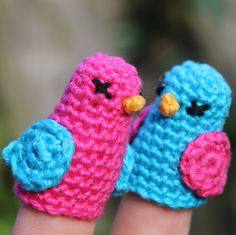 two small crocheted birds sitting on top of each other's fingernails