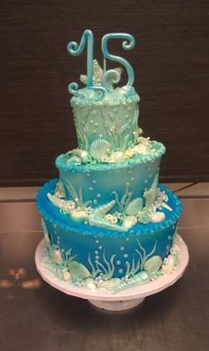 a three tiered cake with blue frosting and sea creatures on it's sides