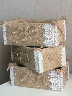 three boxes are stacked on top of each other with lace and pearls around them,