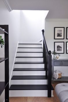 there is a black and white stair case in the living room with pictures on the wall